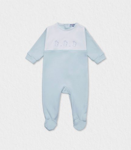 Flat-lay showing ivory organic cotton baby pyjama with cute bunny stitch, rounded collar and full back snaps, placed on pastel linen beside date-palm leaves—ideal for parents seeking Dubai babywear shipped worldwide with breathable, hypoallergenic comfort for newborn nights.